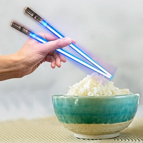 Hand using light-up chopsticks to hold rice in a bowl.