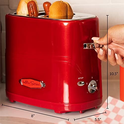 Red retro toaster with two slices of bread and hand adjusting settings.